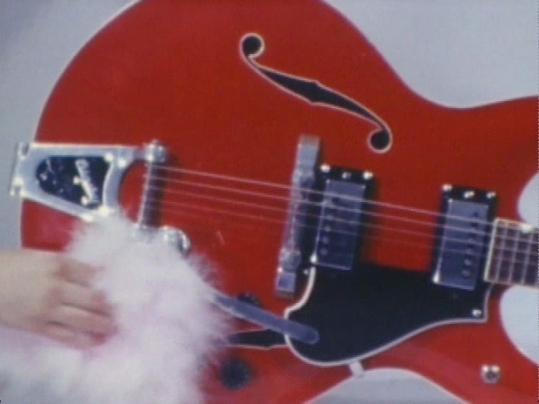 Video Still of a red semi-acoustic electric guitar, getting dusted. Rodney Graham, Sammlung Goetz Munich