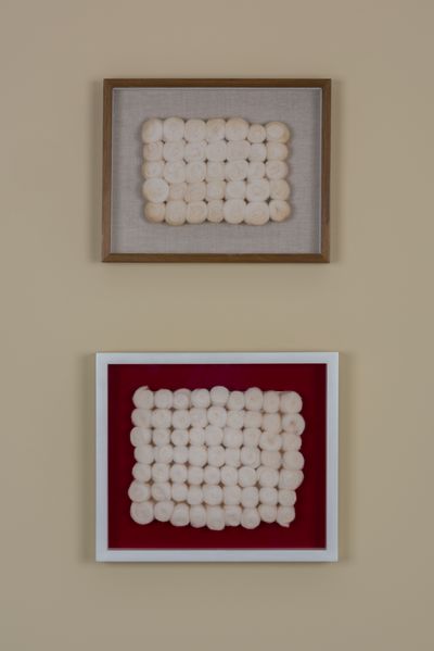 View of the installation of two works by the artist Piero Manzoni, consisting of a gold/white frame, a background of burlap/red painting on which white balls of wool are arranged in rows one above the other. Piero Manzoni, Sammlung Goetz Munich
