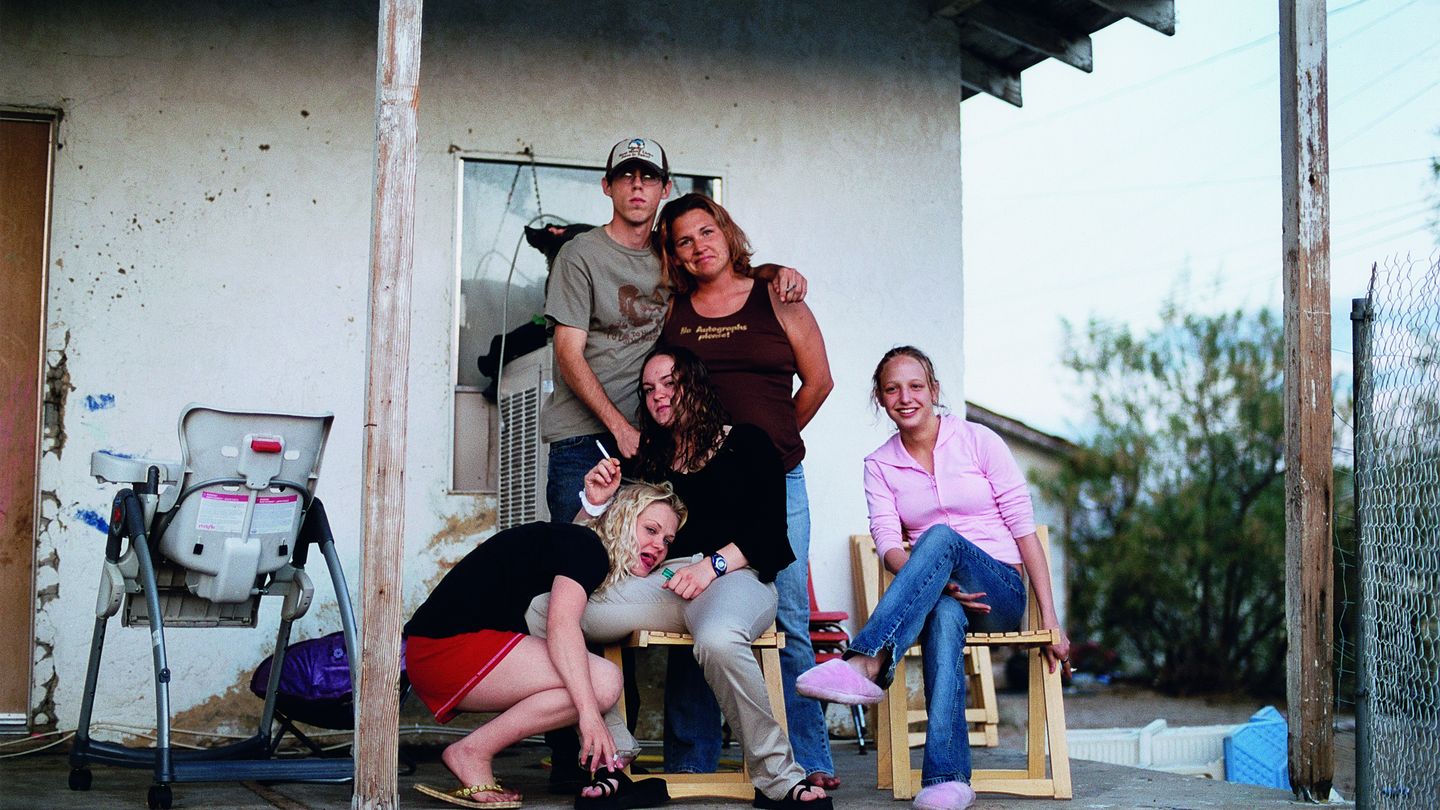 Photograph of an unconventional family in casual clothes on a porch of a run-down house. Tobias Zielony, Sammlung Goetz Munich