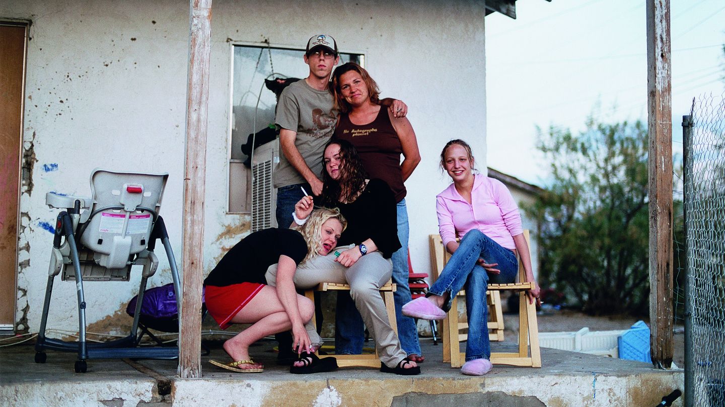 Fotografie einer unkonventionellen Familie in Freizeitkleidung auf einer Veranda eines heruntergekommenen Hauses. Tobias Zielony, Sammlung Goetz München