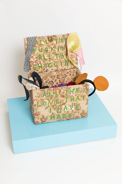 This picture shows an embroidered chest by the artist Tracey Emin. The chest itself is covered with an embroidered fabric of floral pattern. On it Emin embroidered the green letters: "All the fucking, all the shagging, all the love that I have made". Inside the opened chest is frivolous underwear of the artist herself.