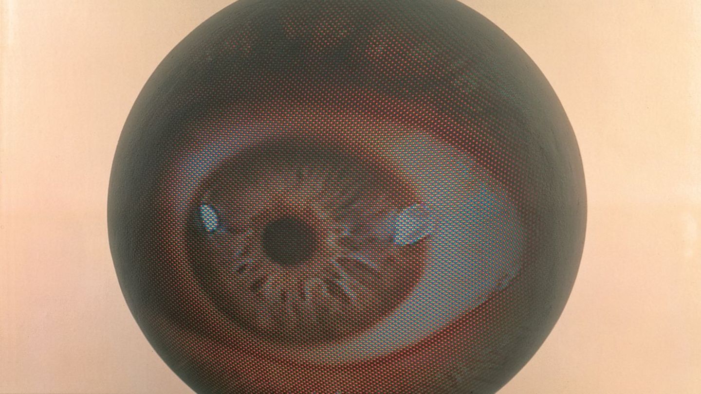 This photograph shows a ball with an eye projected onto it, lying on the floor.