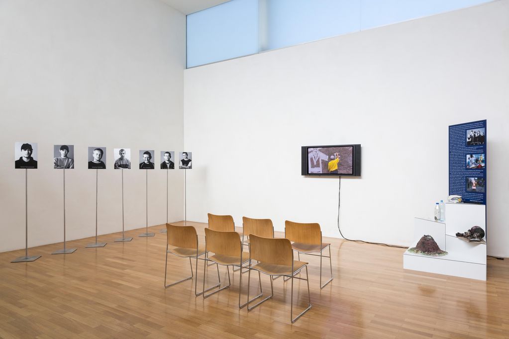 Installation view of the multi-part work "Einstein Class", consisting of a 1-channel video projection, a showcase with objects from the experiments of the Einstein class and eight C-prints on aluminium depicting portraits of the students. Paweł Althamer, Sammlung Goetz Munich