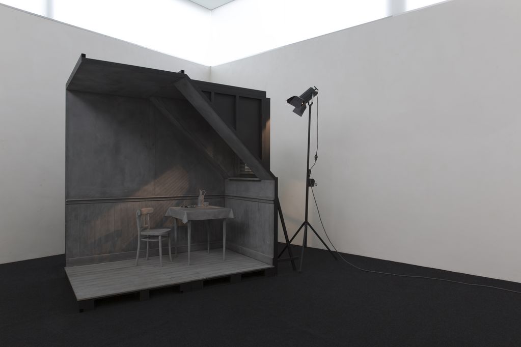 The installation view shows a grey, true-to-scale model of a room corner with a chair, a laid table and a window through which artificial light falls from an outside lamp. Hans Op de Beeck, Sammlung Goetz Munich