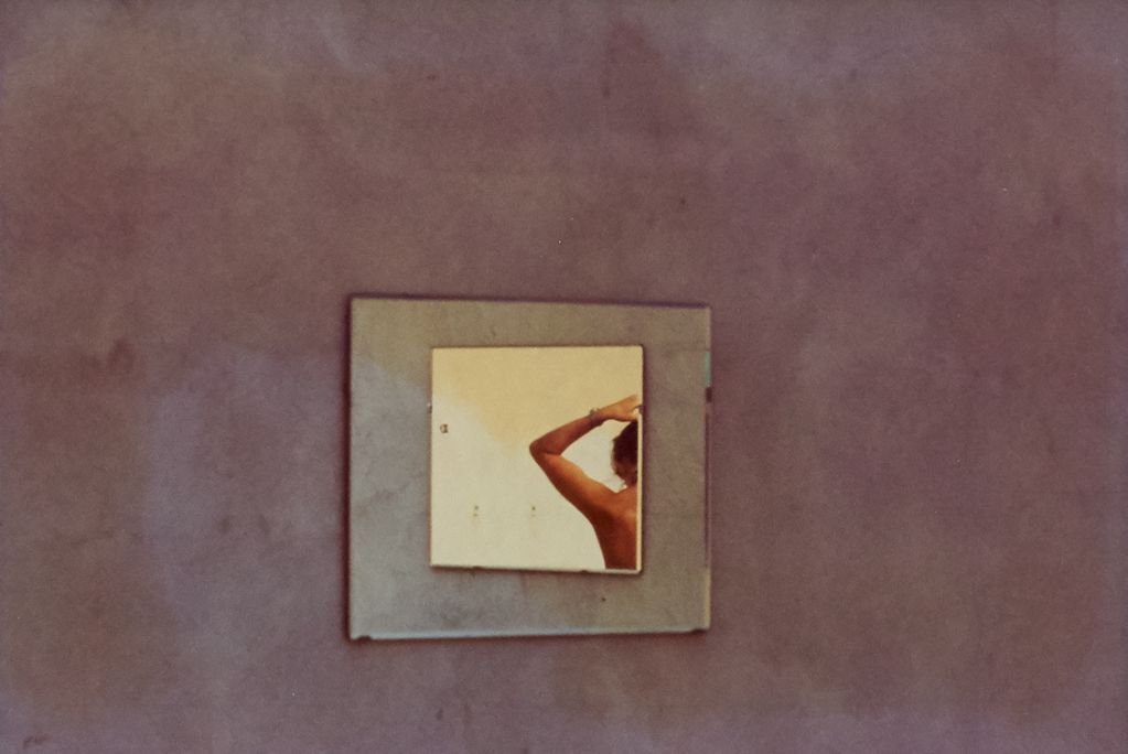 Fotografie eines Spiegels an der Wand, in dem ein Teil des Oberkörpers einer Frau zusehen ist. Luigi Ghirri, Sammlung Goetz München