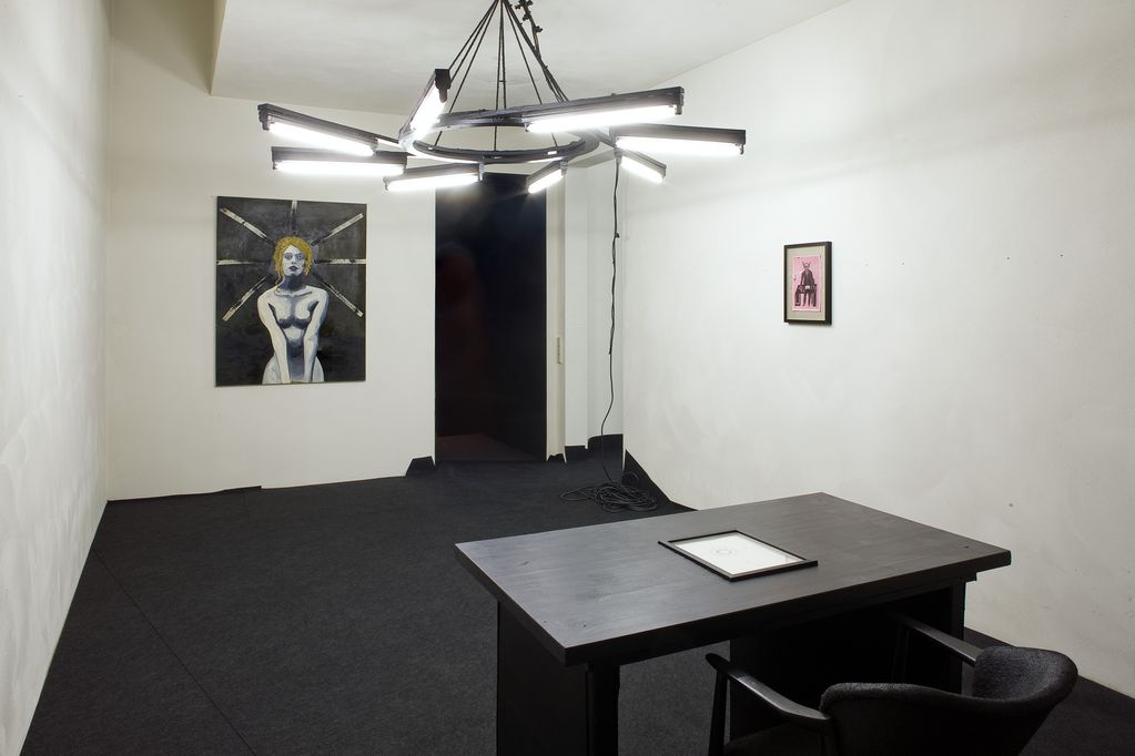 View of the artworks "N.I.B. Office (Samoa leads)" and "white woman". The office consists of a framed collage, a black table, a framed drawing embedded in the tabletop, an upholstered chair, a lamp and a dark painting. Thomas Zipp, Sammlung Goetz Munich