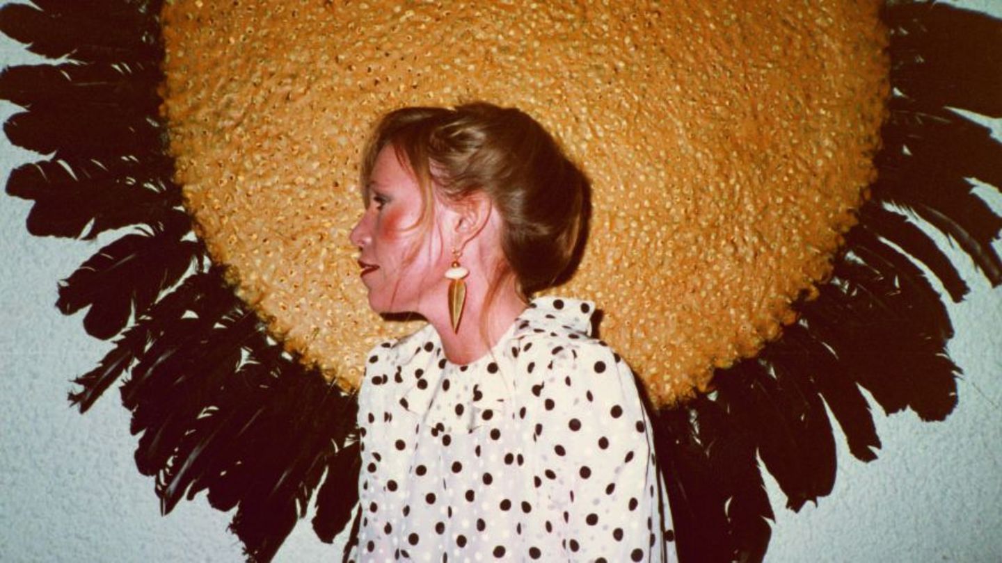 The photograph from the private archive shows the young collector Ingvild Goetz in front of a work by Michael Buthe, consisting of a round golden circle with dark bird feathers attached to its edge. Sammlung Goetz Munich