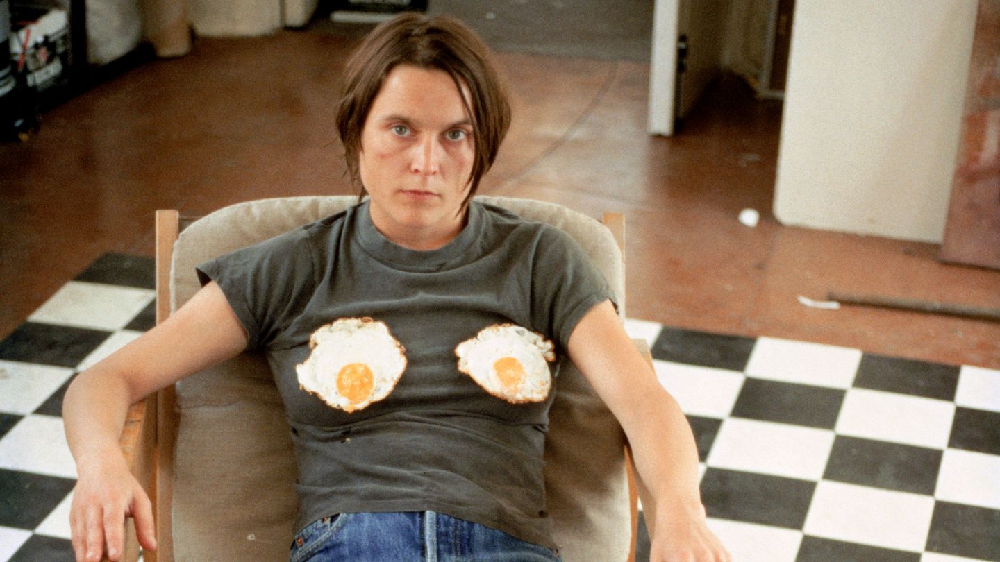 Self-portrait of the artist in an armchair on a black and white checked floor, with fried eggs on her chest. Sarah Lucas, Sammlung Goetz Munich
