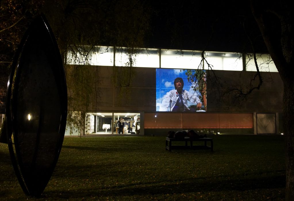 Projection of the work "Lock Again" by the artist Yang Fudong onto the exterior façade of the Goetz Collection building. The still shows a young Chinese man in front of a blue-white sky. Yang Fudong, Sammlung Goetz Munich