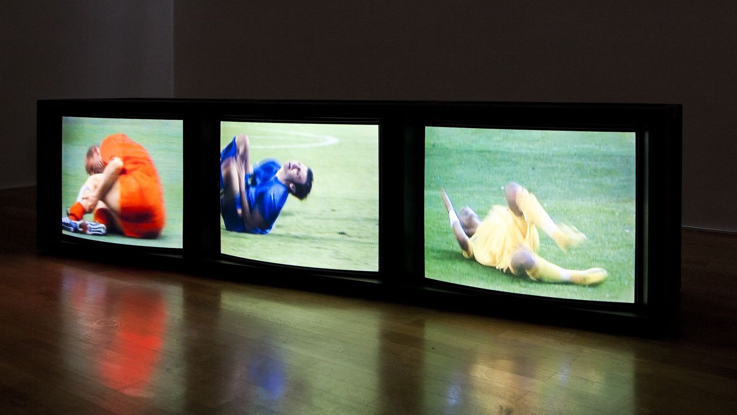 Video installation of three monitors lined up side by side on the floor, all three showing different scenes of falling soccer players in close-up. Paul Pfeiffer, Sammlung Goetz Munich