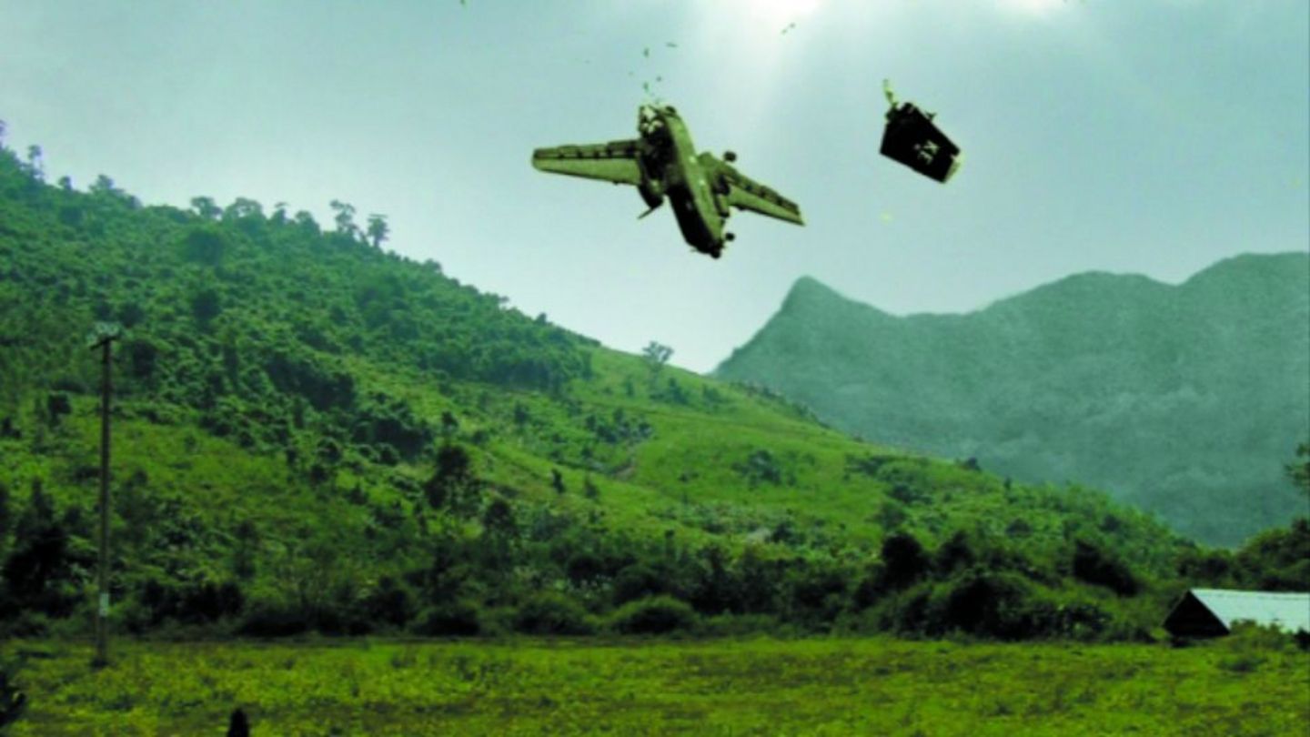 Video Still, das eine grüne, bergige Landschaft Vietnams mit blauem Himmel zeigt, von dem ein getroffenes Militärflugzeug stürzt. David Claerbout, Sammlung Goetz München