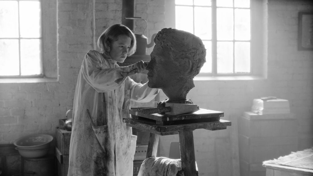 Video Still in black and white of a young woman working on a sculpture depicting a male head. Teresa Hubbard/Alexander Birchler, Sammlung Goetz Munich