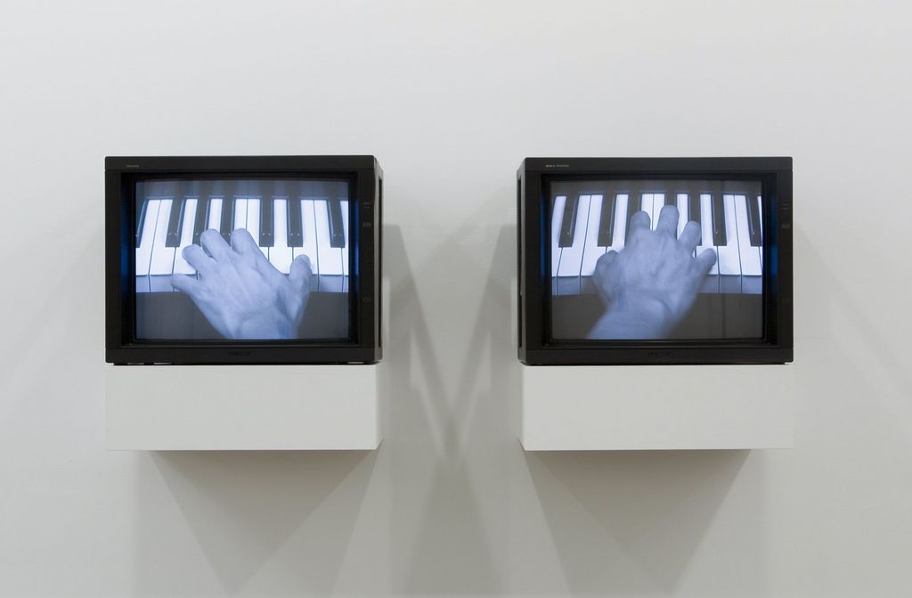 Installation view of the work "The Goldberg Variations" by the artist Tim Lee, consisting of two monitors with black frames, each showing a left and right hand playing the piano on a keyboard. Tim Lee, Sammlung Goetz Munich