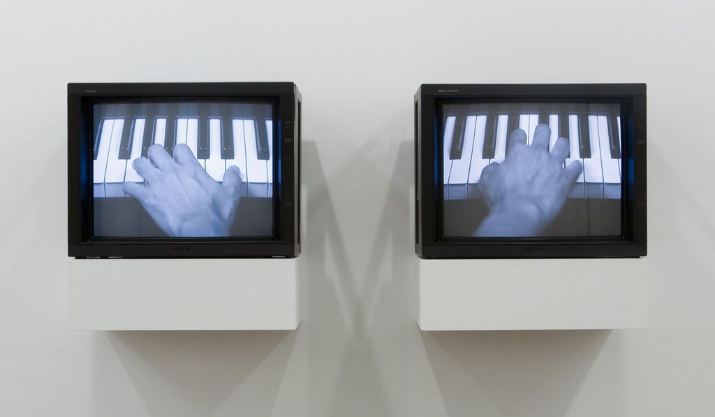 Installationsansicht der Arbeit "The Goldberg Variations" des Künstlers Tim Lee, bestehend aus zwei Monitoren mit schwarzem Rahmen, die jeweils eine linke und rechte Hand beim Klavierspielen auf einer Klaviatur zeigen. Tim Lee, Sammlung Goetz München