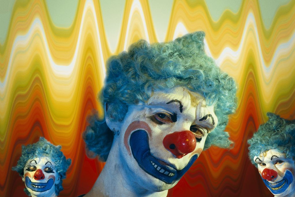 Drei Clowns mit hellblauen Perrücken auf bunt-psychedelischem Hintergrund