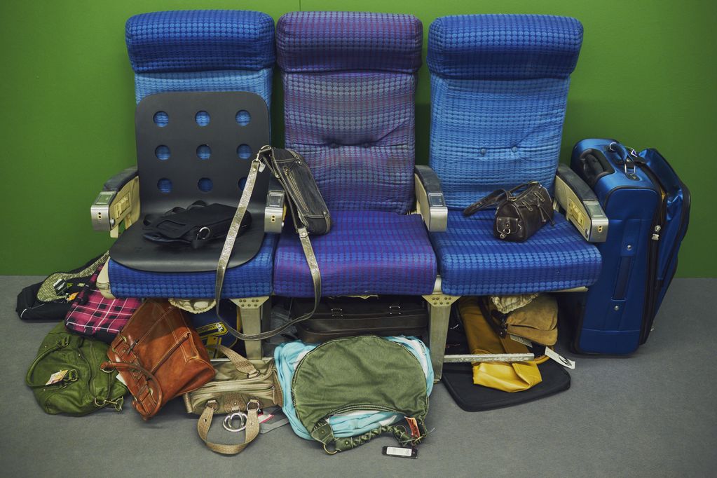 Photography of a stage sculpture consisting of replica S-Bahn seats with various types of luggage underneath and next to them. Ryan Trecartin/Lizzie Fitch, Sammlung Goetz Munich