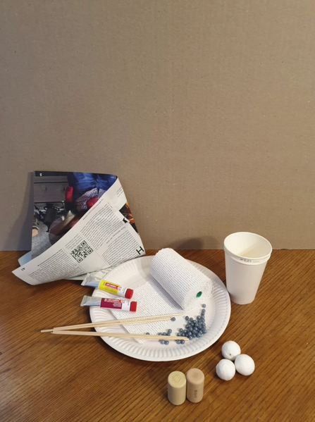 Selection of craft materials needed for the tutorial, including e.g. paper cups and newspaper