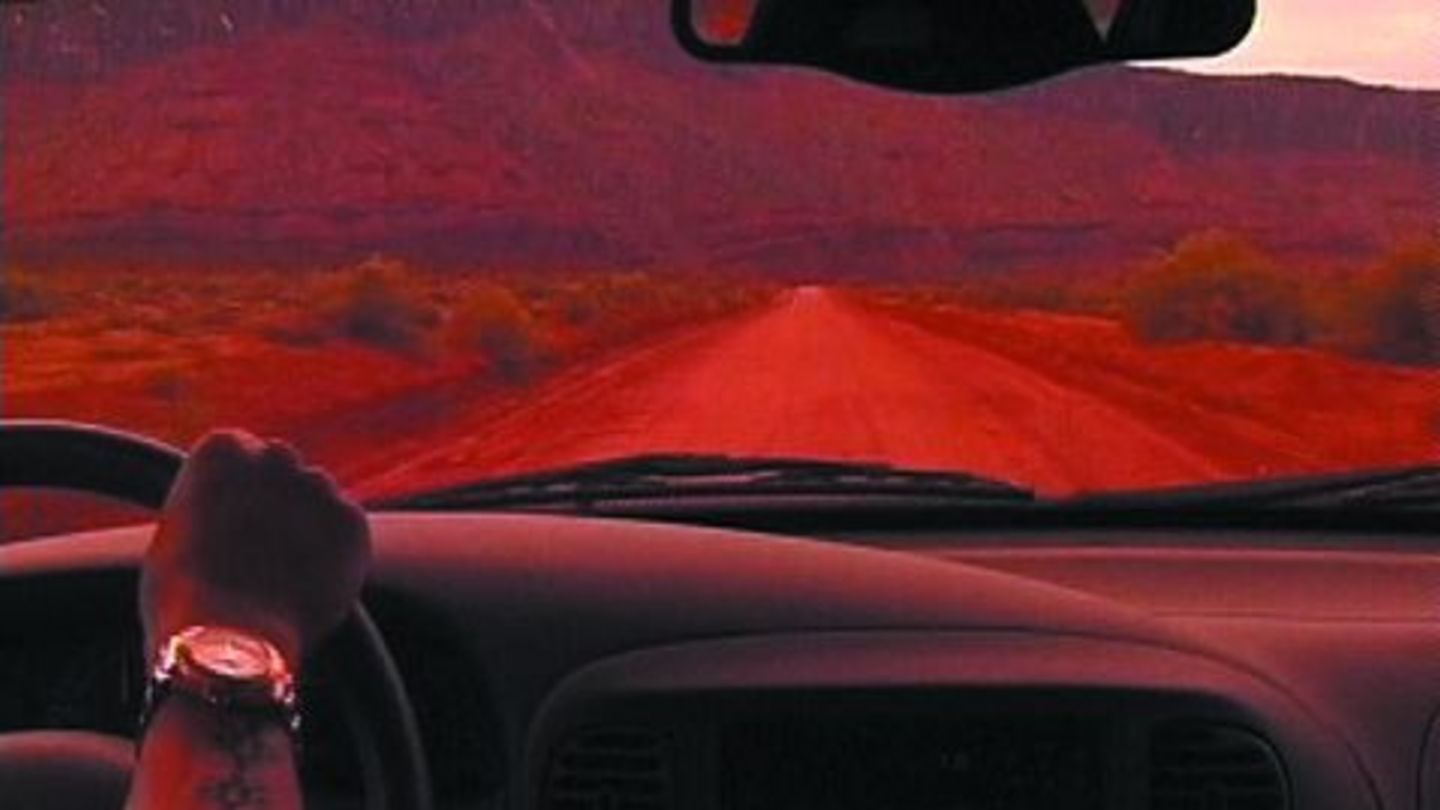 Video Still einer in rosarotem Licht getauchten Autofahrtszenerie, von der Rückbank durch die Frontwindschutzscheibe aus gesehen. Olaf Breuning, Sammlung Goetz München