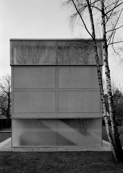Black and white photograph of the short facade side of the rectangular exhibition building of the Sammlung Goetz. Two tall birch trees jut into the picture on the right.