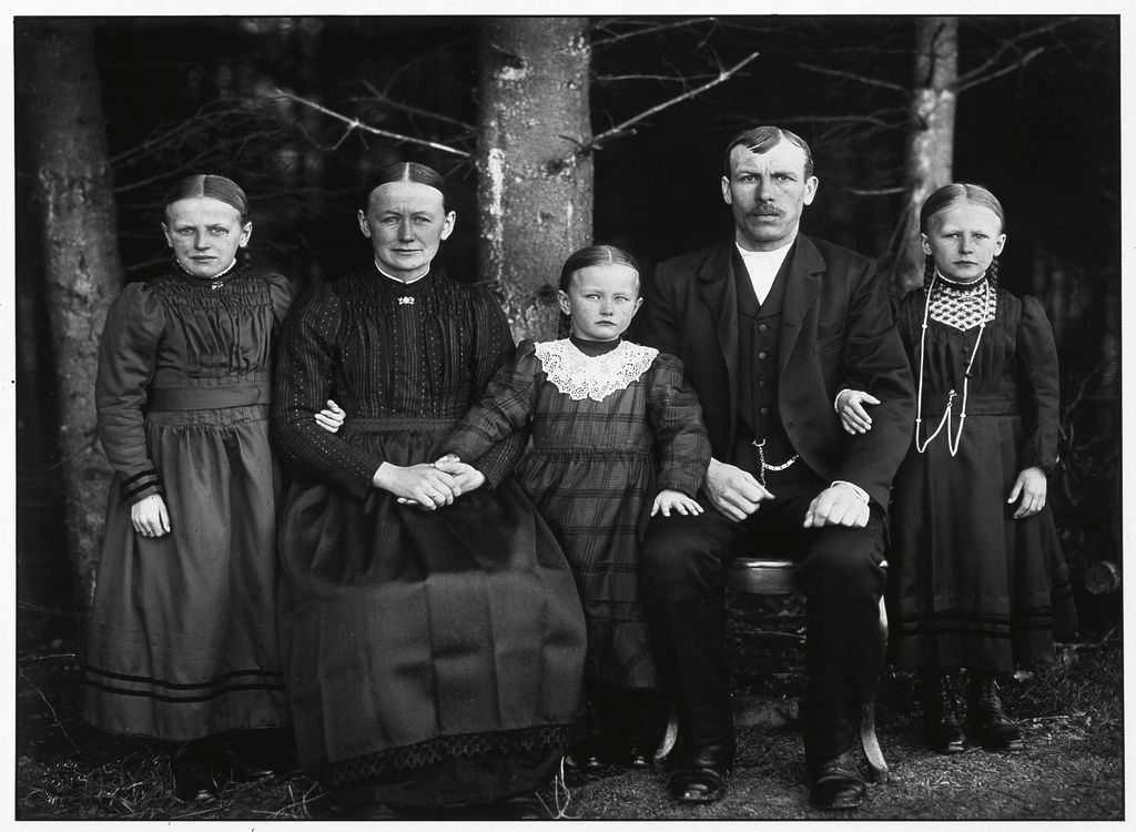 Black and white photograph showing a simple German family at the beginning of the 20th century. The parents are sitting on chairs, while the three young daughters stand at their sides. All wear a severe parting, their Sunday best, and look sternly at the camera. August Sander, Sammlung Goetz Munich