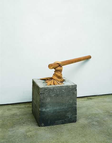 Here you can see a sculpture consisting of a cement cube, a leather cloth and a thick wooden stick. The leather cloth is partly cast into the cement block, the rest of it seems to be wrung out of the wooden stick as if by magic.