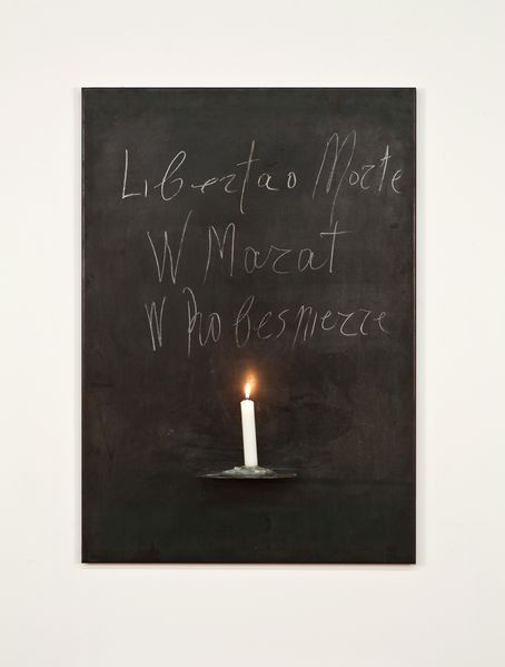 Wall object consisting of an anthracite-coloured steel plate and a white, burning stick candle in the centre of its lower surface. Above the candle is written in Kounellis' handwriting with white chalk "Liberta o morte. Marat/Robespierre". Jannis Kounellis, Sammlung Goetz Munich