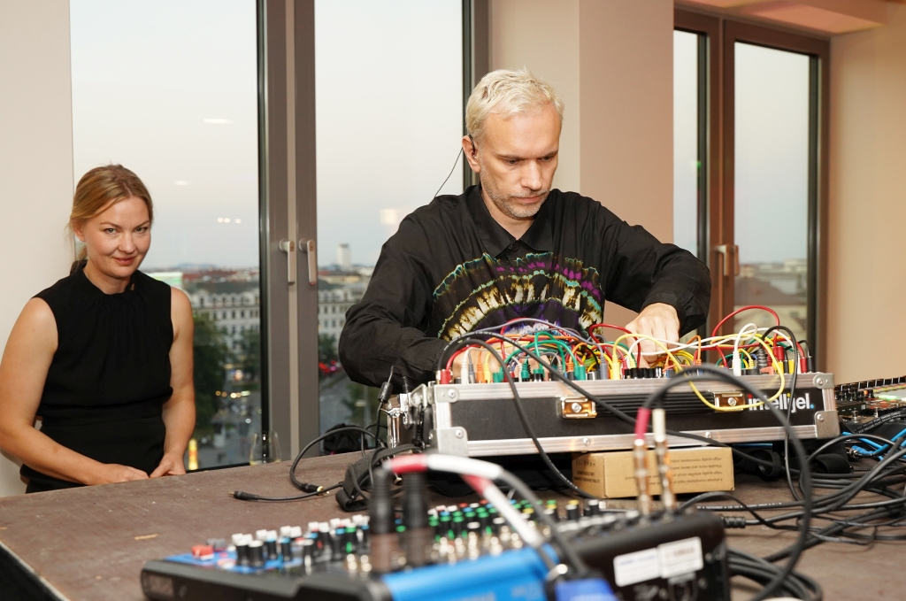 Hans Berg stands at a mixing desk, with Nathalie Djurberg behind him