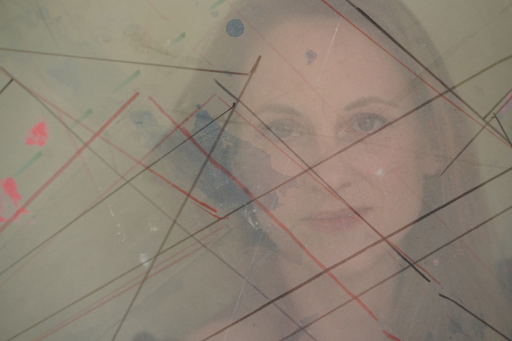A portrait of the artist superimposed with an abstract geometric sketch of red and black parallel and intersecting lines