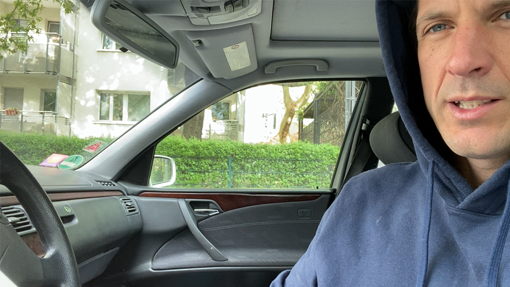 Cyrill Lachauer sitzt in einem blauem Kapuzenpullover in seinem Auto