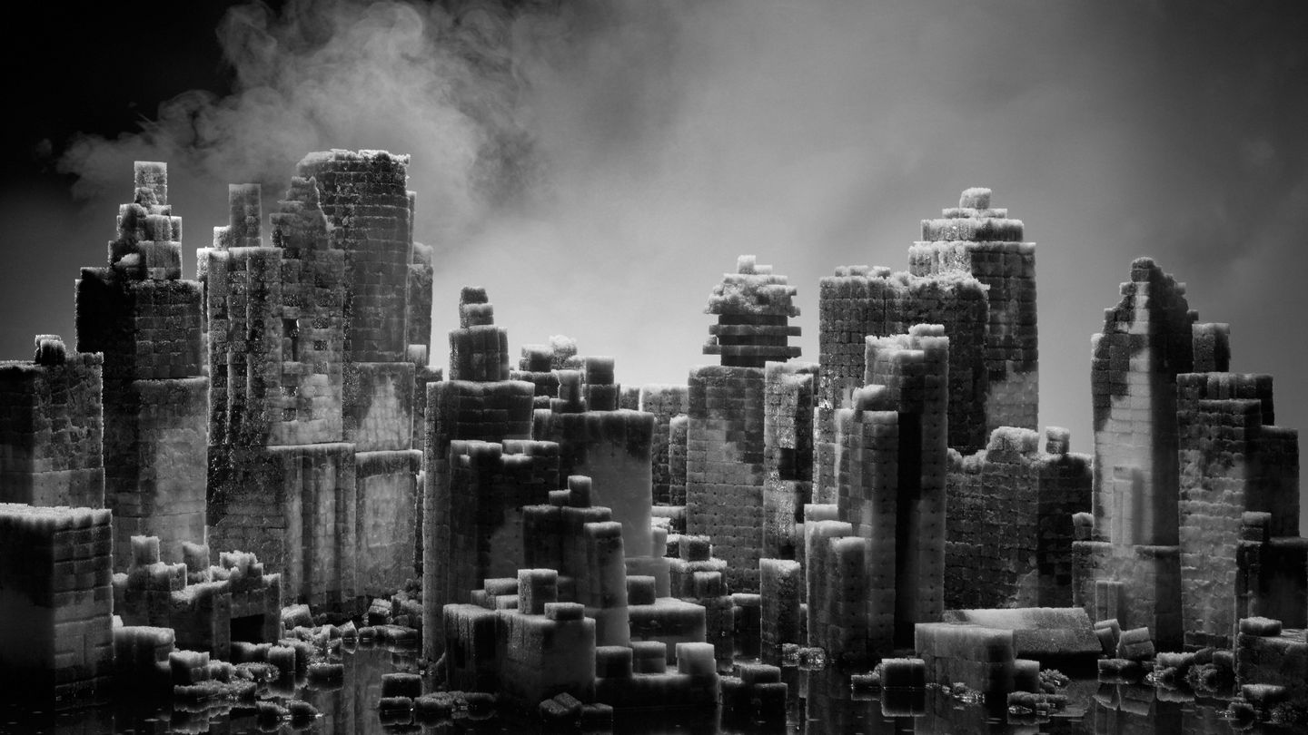 This black-and-white photograph shows a model skyline made of sugar cubes from which white mist is rising. Hans Op de Beeck, Sammlung Goetz Munich