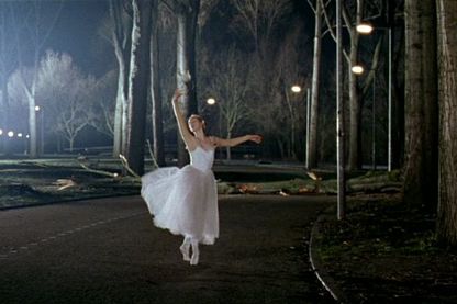 Video Still, das eine Balletttänzerin beim Spitzentanz in weißem Kostüm auf einem Weg in einem beleuchteten Park bei Nacht zeigt. Guido van der Werve, Sammlung Goetz München 
