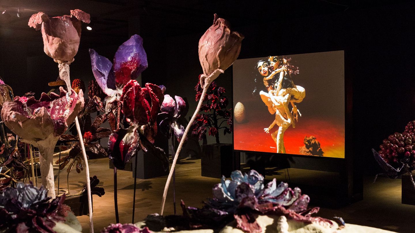 Detail of the room installation work "The Experiment", consisting of 130 flowers, 34 pedestals and 3 canvases. The flowers consist of many different materials and populate the black-painted room. Nathalie Djurberg, Sammlung Goetz Munich