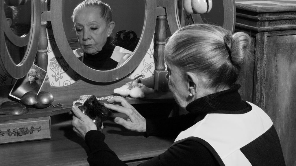Schwarzweißfoto von einer Frau im Spiegel mit einem Gegenstand in der Hand 