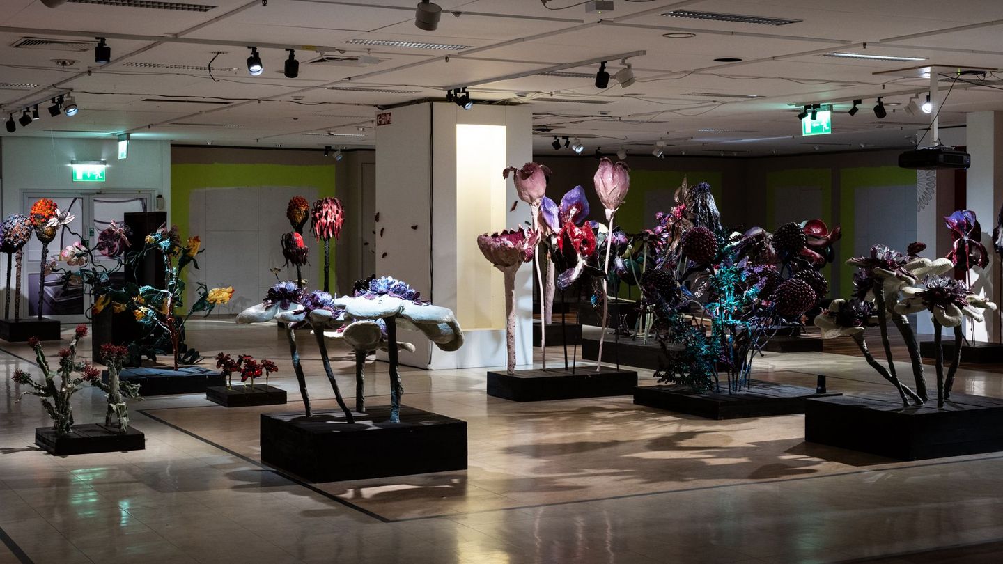 Gloomy walk-in installation with oversized flower sculptures