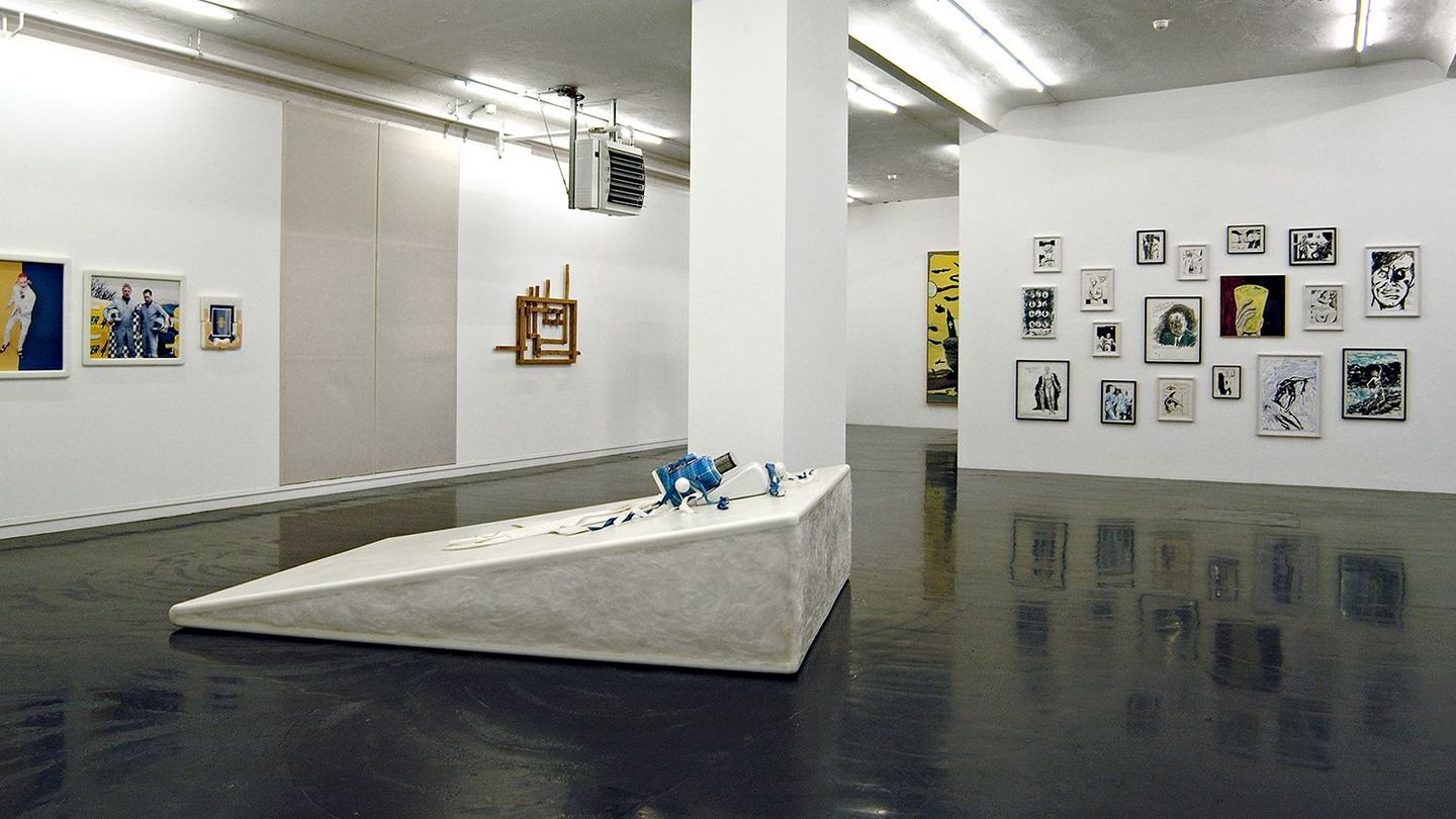 Exhibition view with a sculpture in the center of the image, as well as photographic works by Matthew Barney on the left wall and ink drawings by Raymond Pettibon on the wall behind the sculpture. Matthew Barney, Raymond Pettibon; Sammlung Goetz Munich