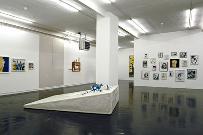 Ausstellungsansicht mit einer Skulptur in der Bildmitte, sowie fotografischen Arbeiten von Matthew Barney an der linken Wand und Tuschezeichnungen von Raymond Pettibon an der Wand hinter der Skulptur. Matthew Barney, Raymond Pettibon; Sammlung Goetz München
