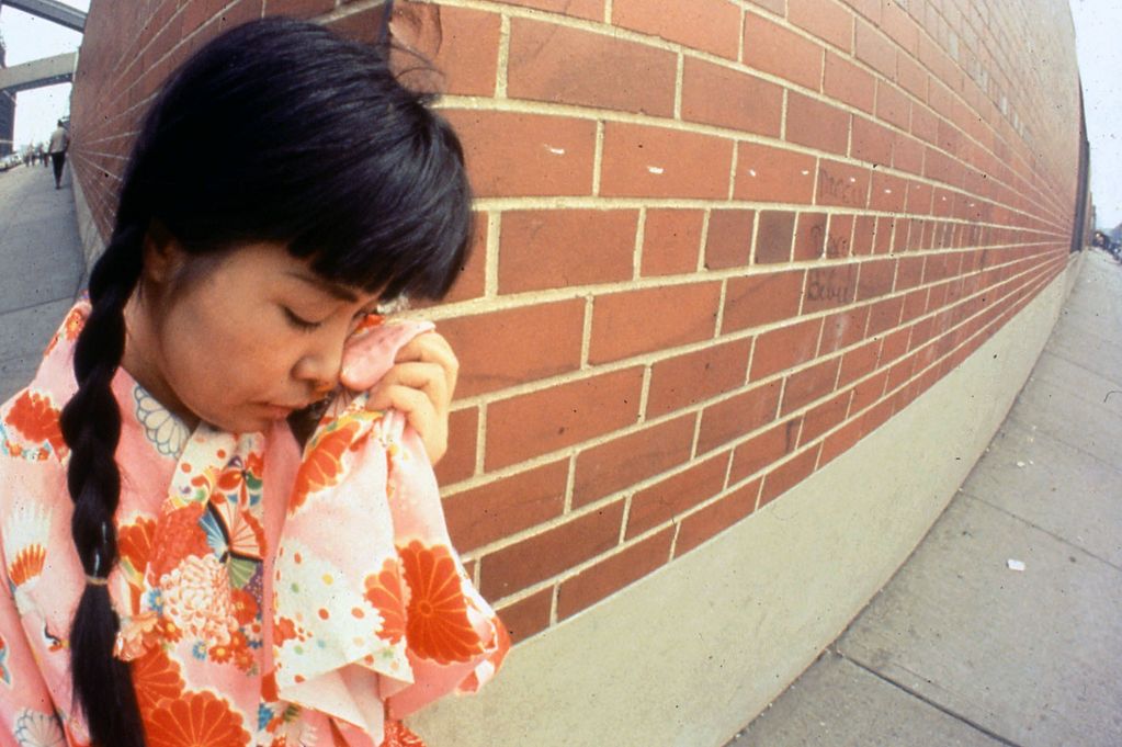 Dieses Diapositiv zeigt die Künstlerin an einer Straßenecke in New York, wo sie ihre Tränen mit einem Taschentuch, welches das gleiche Muster wie ihr Kimono hat, trocknet.