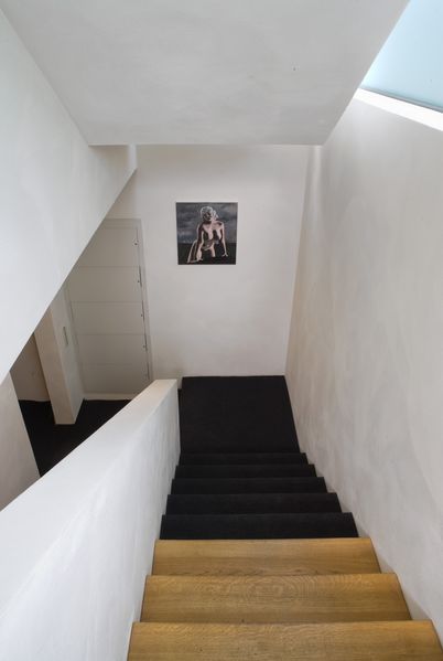 Ansicht des Treppengangs der Sammlung Goetz, die zum unteren Geschoss führt, an der Wand hängt eine dunkle Malerei von einer nackten Frau. Thomas Zipp, Sammlung Goetz München