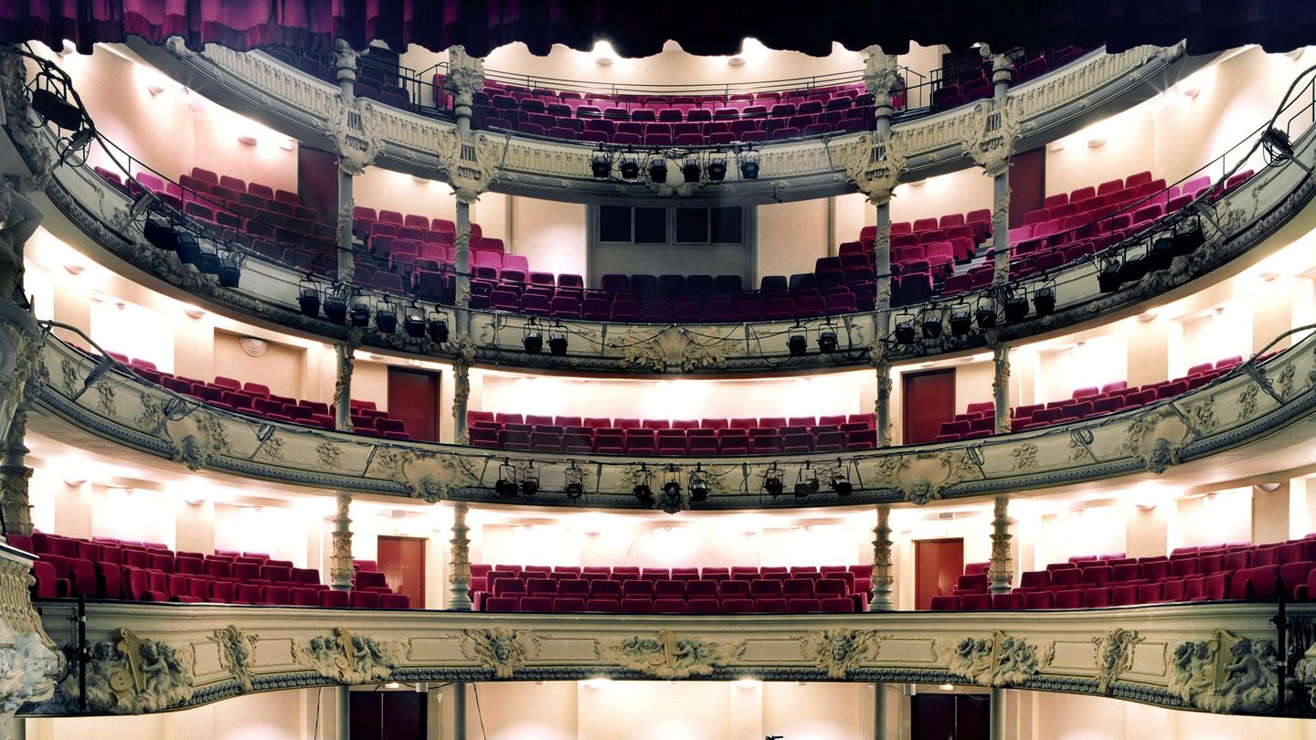 This photograph shows an empty baroque concert hall respectively opera hall from the stage. On the stage are music stands, an electric piano and other musical equipment. Candida Höfer, Sammlung Goetz Munich