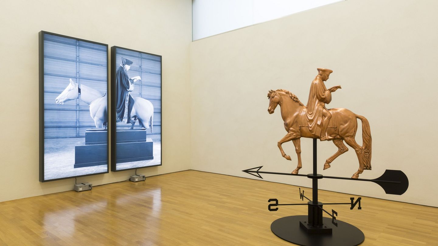 Exhibition view of two works by the artist Rodney Graham in the building of the Sammlung Goetz. One work is a photographic diptych in black and white of an equestrian statue, which also stands in the centre of the room as a sculptural roof ornament with compass direction indicators. Rodney Graham, Sammlung Goetz Munich