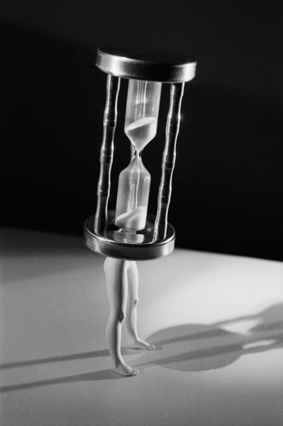 Black and white photograph of hourglass with doll legs
