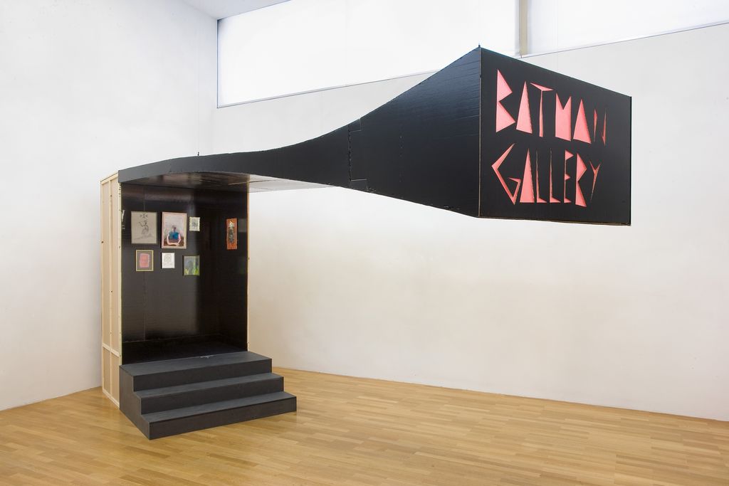 View of the installation "Batman Gallery", a small black exhibition space, to which three also black steps lead. The mini-gallery has an extremely elongated canopy, the end of which is adorned with the letters "Batman Gallery". The miniature exhibition room also contains works by the artist. Andy Hope 1930, Sammlung Goetz Munich
