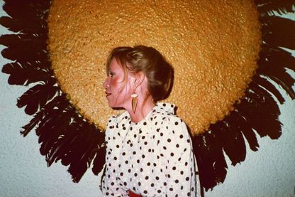 Das Foto aus dem Privatarchiv zeigt die junge Sammlerin Ingvild Goetz vor einer Arbeit Michael Buthes, bestehend aus einem runden goldenen Kreis mit dunklen Vogelfedern an dessen Rand befestigt. Sammlung Goetz München