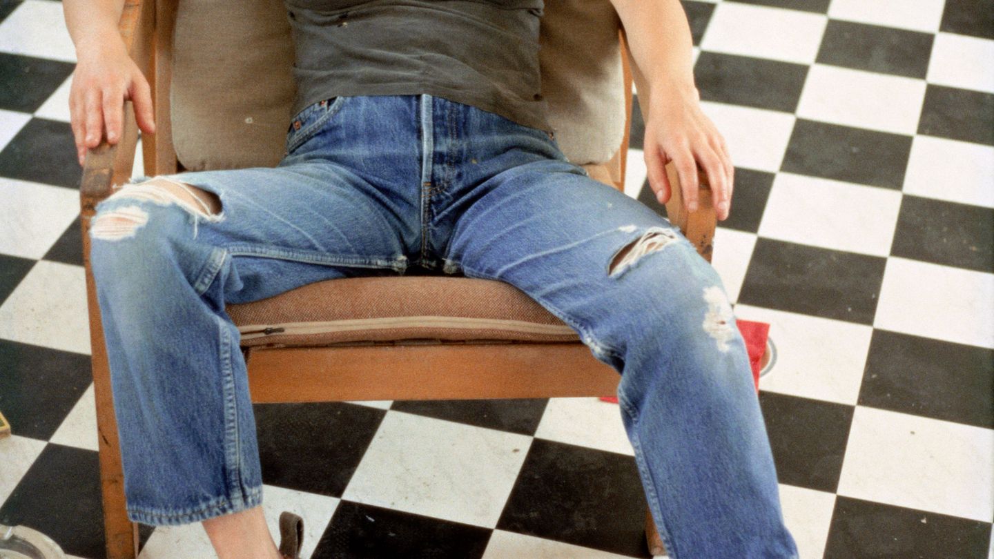 Self-portrait of the artist in an armchair on a black and white checked floor, with fried eggs on her chest. Sarah Lucas, Sammlung Goetz Munich