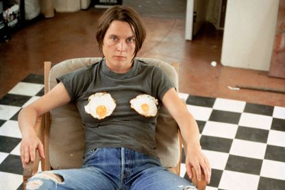 Selbstporträt der Künstlerin in einem Sessel auf schwarzweiß kariertem Boden, mit gebratenen Spiegeleiern auf der Brust. Sarah Lucas, Sammlung Goetz München