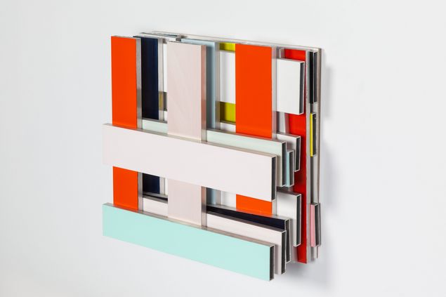 Wall object made of rectangular metal bars cut to size and painted in different colors, forming a kind of square grid. 