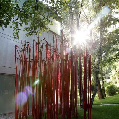 © Ulrike Ottinger Installation vor der Sammlung Goetz, lange rote Stoffbänder hängen von hölzernen Masten, Ulrike Ottinger Sammlung Goetz, München
