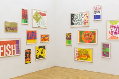 Ansicht einer Ecke eines Ausstellungsraumes der Sammlung Goetz, mit verschieden großen, gerahmten und vielfarbigen Siebdrucken an beiden Wänden platziert. Sister Mary Corita Kent, Sammlung Goetz München