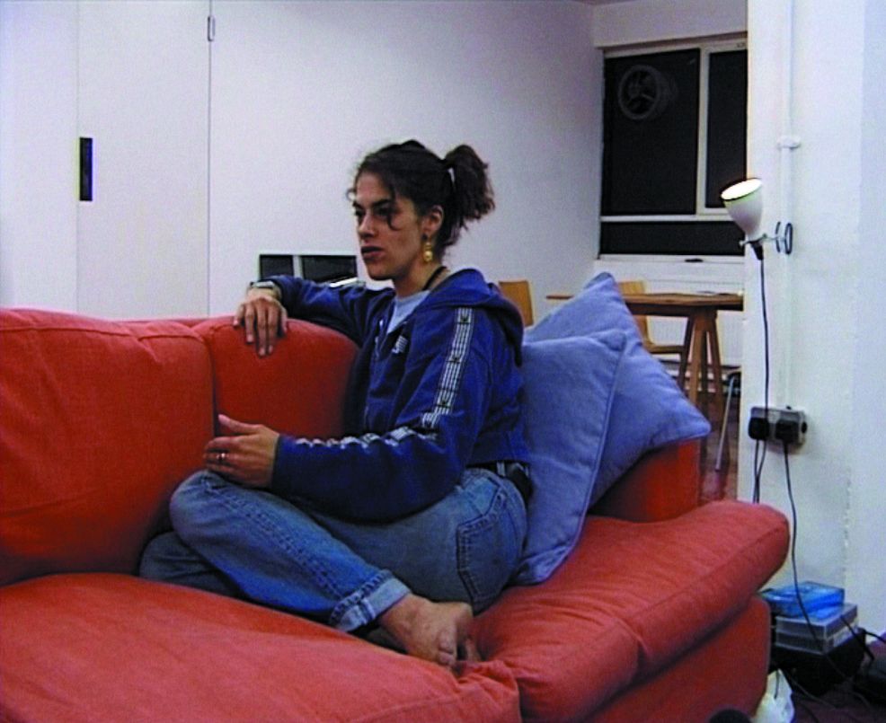 Video Still, das die Künstlerin Tracey Emin auf einer roten Couch sitzend zeigt. Tracey Emin, Sammlung Goetz München