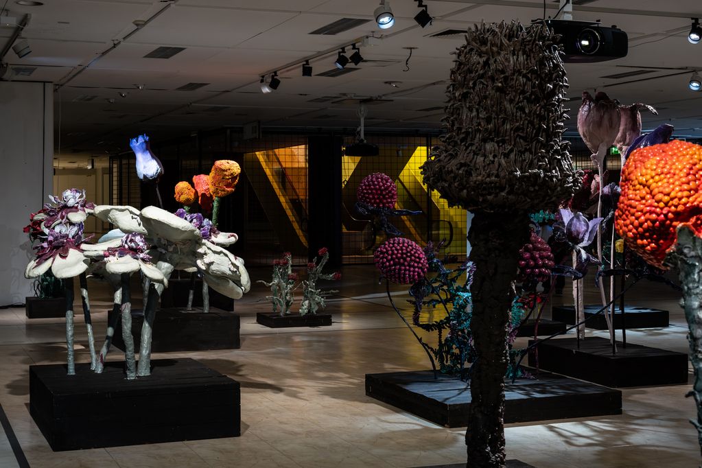 Somber walk-through installation with oversized flower sculptures